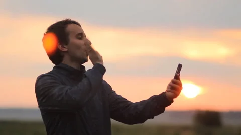 A man makes a video call on the phone. Beautiful sunset on the background Stock Footage 64600904