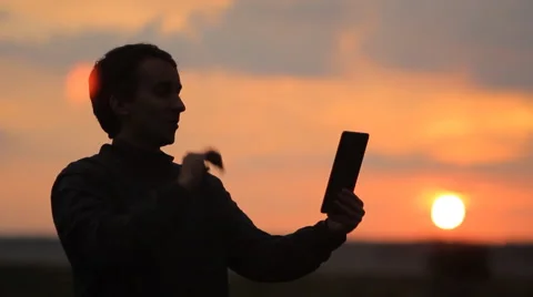 A man makes a video call on the tablet. Beautiful sunset on the background Stock Footage 64601816