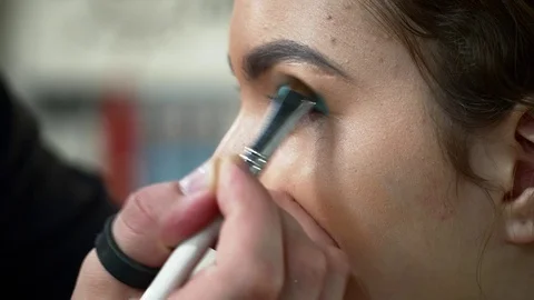 Man makeup artist making the face art with blue shadows for woman Stock Footage 76570408