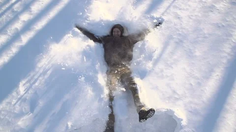 A man making angel shapes in the snow outdoors on a winter day Edmonton, Alberta Vídeo Stock 276801995