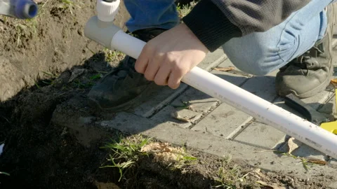 Man making an automatic system for watering plants and lawn in the garden. 4K 库存影片 106940103