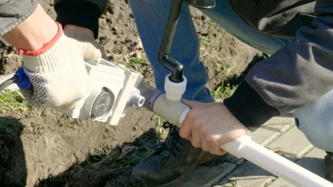 Man making an automatic system for watering plants and lawn in the garden. 4K Stock Footage 106940334