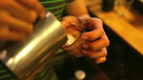 Man making beautiful latte art in glass cup. Coffee with pretty latte art Foam. 動画素材 334650091