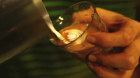 Man making beautiful latte art in glass cup. Coffee with pretty latte art Foam. 動画素材 334650206