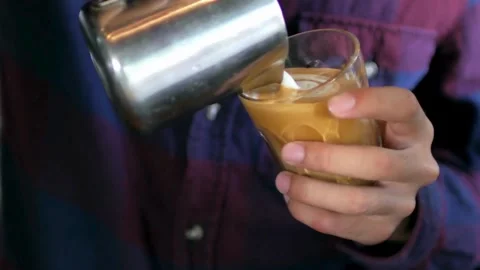 Man making beautiful latte art in glass cup. Coffee with pretty latte art Foam. 動画素材 334650353
