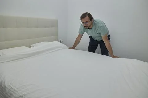 Man making the bed in a modern bedroom Stock Photos