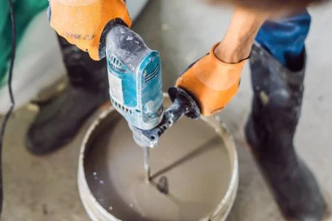 Man making cement with a construction mixer in a bucket Stock Photos