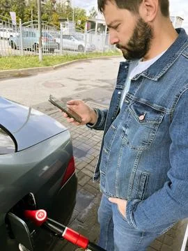 Man making contactless payment using smartphone for refueling car at gas st.. Stock Photos