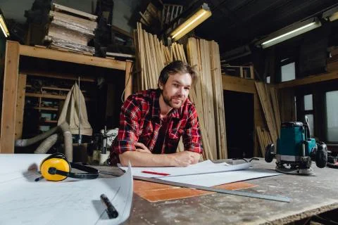 Man making draft plan using pencil on the table with workshop on background. Stock Photos