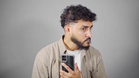 Man making facial expressions while holding smartphone Stock Footage 314785566