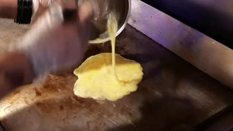 The man is making fried eggs. Put the mixed egg on the stove and fry it Stock Footage 172050218
