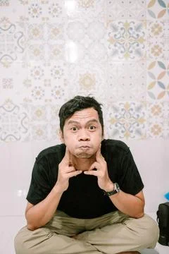 Man making funny face with puffy cheeks against patterned background Stockfoto's
