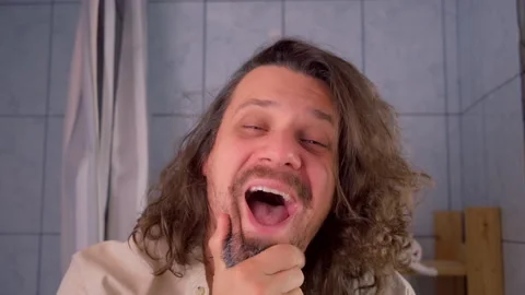 Man making funny faces laughing hysterically looking in bathroom mirror. Stock Footage 312099296
