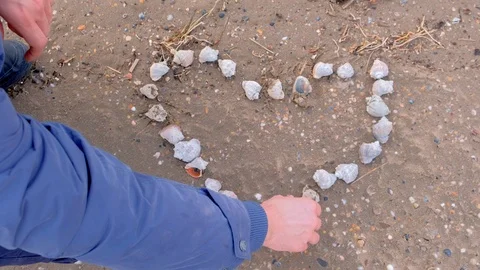 Man is making heart from shells on sea sandy beach, hands closeup. Stock Footage 117906611