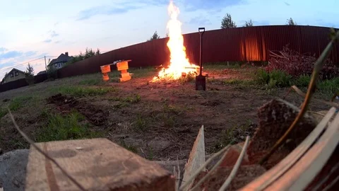 A man making huge bonfire on cottage backyard, burning wood waste Stock Footage 74928592