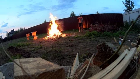 A man making huge bonfire on cottage backyard, burning wood waste Video stock 74928736