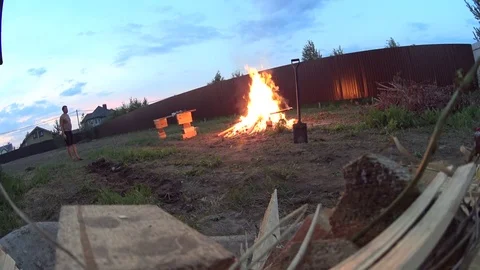 A man making huge bonfire on cottage backyard, burning wood waste Video stock 74928858
