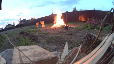 A man making huge bonfire on cottage backyard, burning wood waste Video stock 74928870