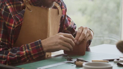 Man making leather wallet at a workshop. Concept of handmade craft production of Stock Footage 140520825