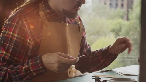 Man making leather wallet at a workshop. Concept of handmade craft production of Stock Footage 140522381
