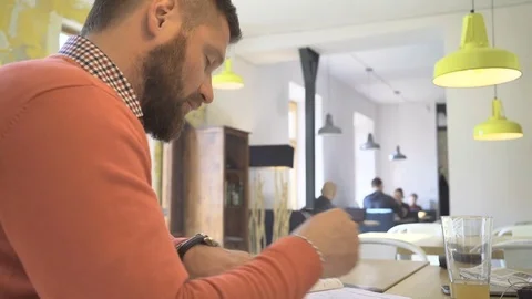 Man making notes in calendar, looking at camera, close profile shot, cafe Vídeo Stock 73292319