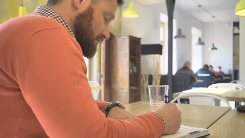 Man making notes in calendar, writing, close profile shot, in cafe, steadicam 動画素材 73292097