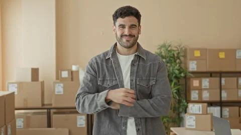 Man making ok sign with right hand among stacked shipping boxes and parcels.. 動画素材 339174673