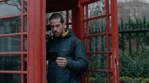 Man making a phone call at red telephone box Stock Footage 130979443