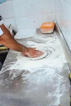 A man is making a pizza on a counter Stock Photos