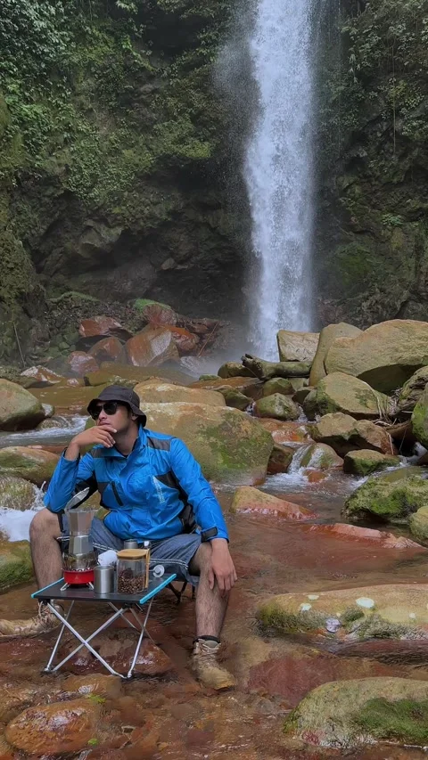 Man Making Pour Over Coffee by Waterfall in Jungle Vertical Dolly Shot Stock Footage 321104381