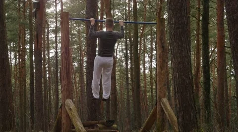 Man making pull-ups in the pine woods. Gym on fresh air Stock Footage 48547900
