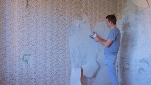 Man is making renovation removing wallpapers from wall, construction work. Stock Footage 124948133