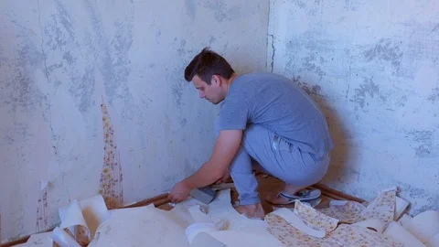 Man is making renovation removing wallpapers from wall, construction work. Stock Footage 124948509