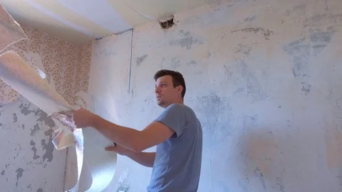 Man making renovation removing wallpapers from wall, ceiling, construction work. Stock-Footage 124948682