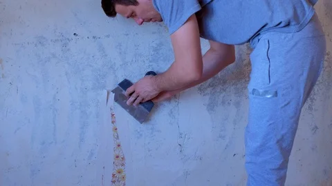 Man is making renovation removing wallpapers from wall, construction work. Video stock 129459403