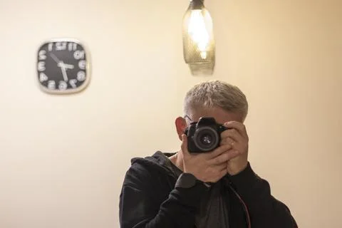 Man making a self portrait in the mirror using digital camera. Concept Stock Photos
