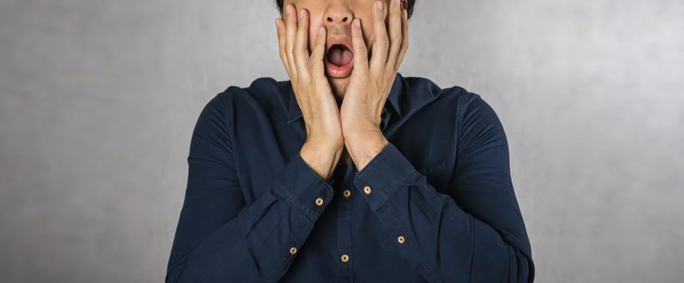 Man making shock expression, hands covering face gesture Stock Photos