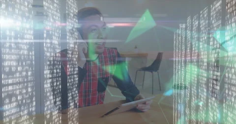 Man making smartphone call and tapping tablet in tech office with binary code Stock Footage 307450408