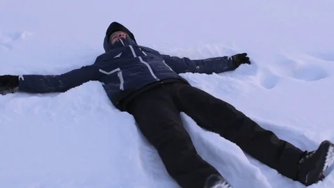 Man is making snow angel in deep snow, having fun in winter Stock-Footage 74434346