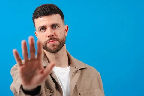 Man making stop gesture with hand against blue background Stock Photos