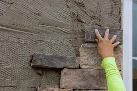 Man making texture of wall facing with decorative stone tiles bricks Stock Photos