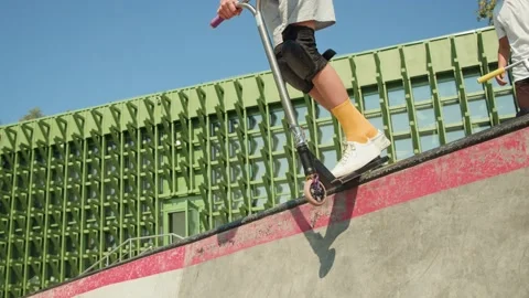 Man making trick on kick scooter in concrete bowl, air extreme in skate park Stock Footage 220199324