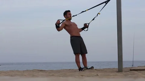 Man making trx exercise on the beach Stock Footage