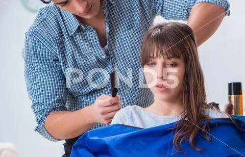 Man male hairdresser doing haircut for woman Stock Photos