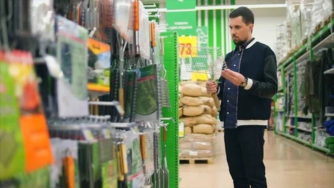 Man in the mall chooses hand grid for grill. He looking carefully Stock Footage 76769123