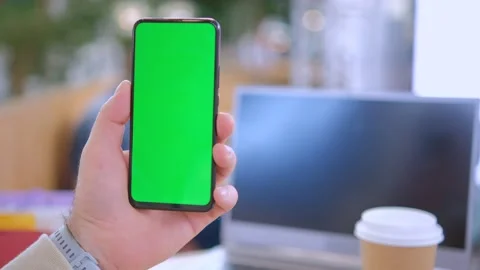 Man at mall Sits by the table using Smartphone with Green Mock-up Screen, Doing Vídeo Stock 252204236