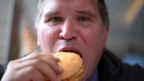 The man man eats the sandwiches hungrily biting off a big bite, drinking a drink Stock Footage 107308155