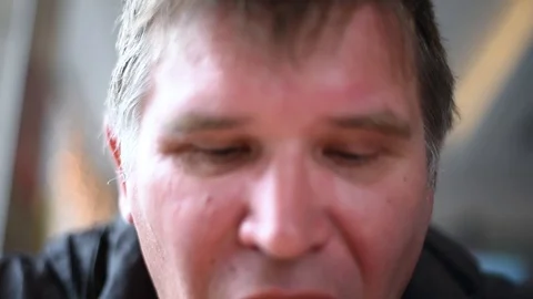 The man man eats the sandwiches hungrily biting off a big bite, drinking a drink Stock Footage 107308157