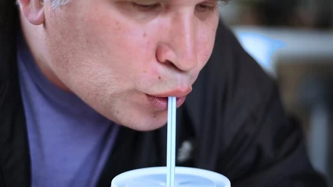 The man man eats the sandwiches hungrily biting off a big bite, drinking a drink Stock Footage 107308190