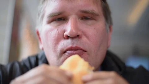The man man eats the sandwiches hungrily biting off a big bite, drinking a drink Stock Footage 107308204